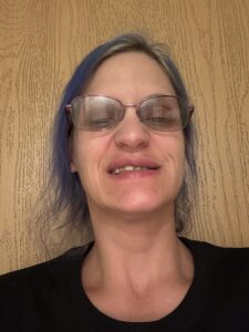 white woman with brown shoulder length hair wearing glasses